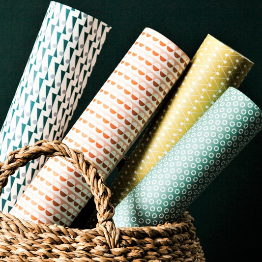 a woven basket filled with rolls of geometric wrapping paper