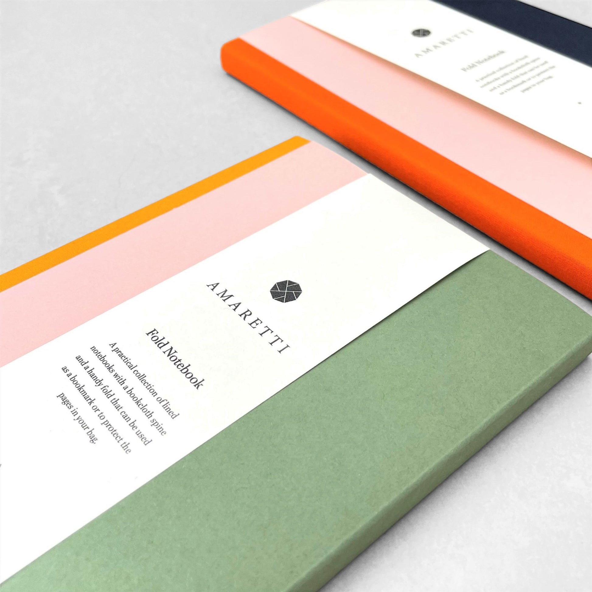 A lined notebook with striped block colours in mustard, rose and green by Amaretti Design