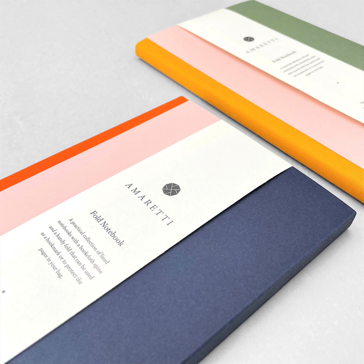 A lined notebook with striped block colours in orange, rose and navy by Amaretti Design