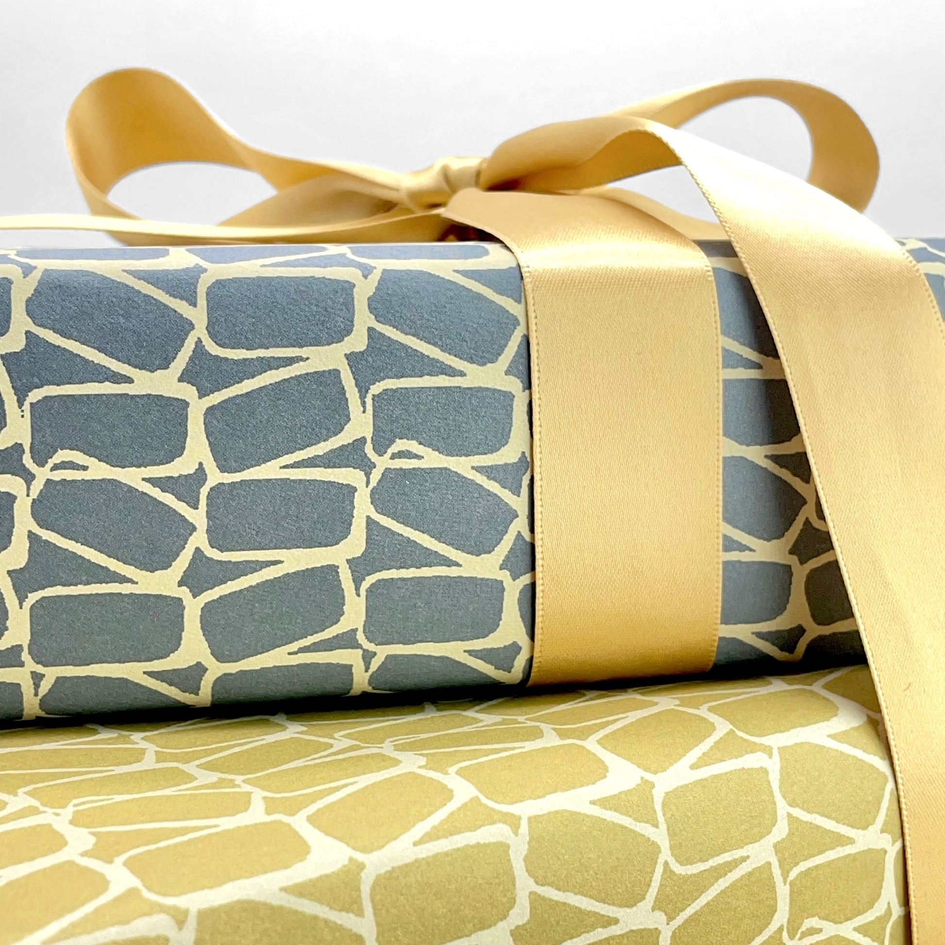 wrapping paper by Anne Davison Studio. Creamy domino outlined shapes on a dusky blue background. Close up