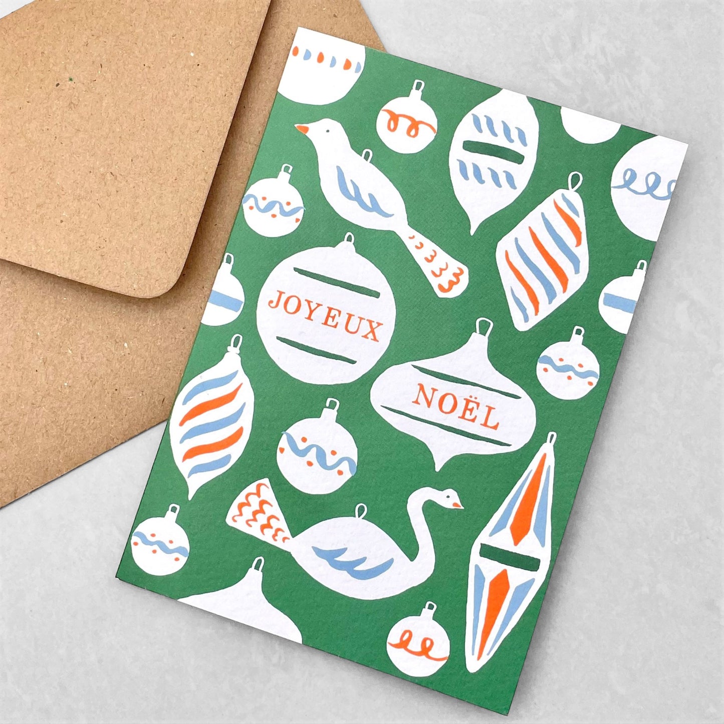 Greetings card with baubles and decorations and the message "Joyeux Noel" in green , white, blue and red. Christmas card by Ariana Martin