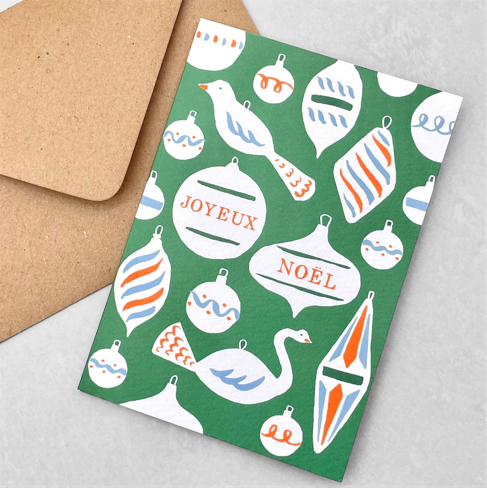Greetings card with baubles and decorations and the message "Joyeux Noel" in green , white, blue and red. Christmas card by Ariana Martin