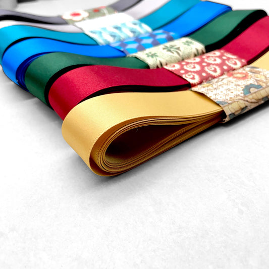 Satin ribbon 25mm wide and 5 metres long, presented with a patterned paper band. colour - honey gold