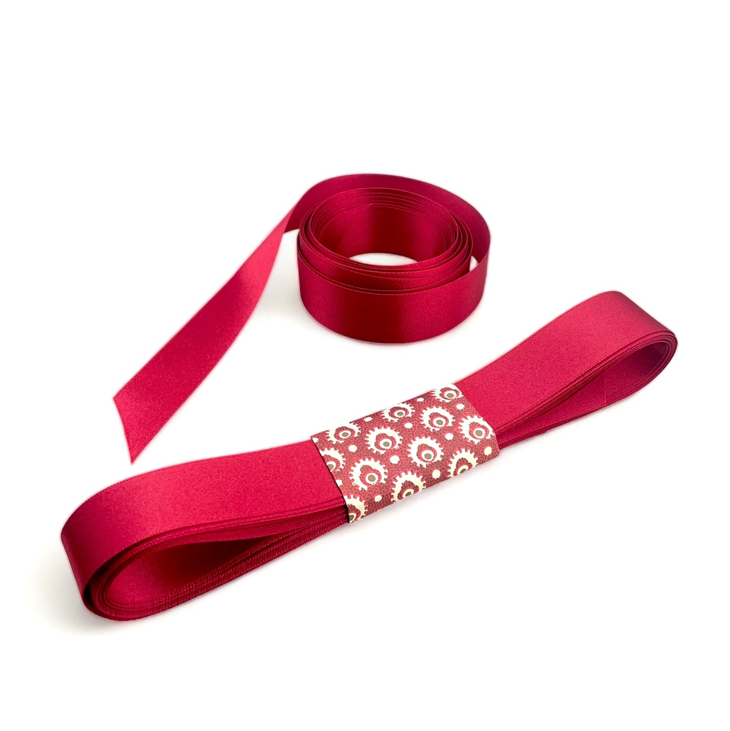 Satin ribbon 25mm wide and 5 metres long, presented with a patterned paper band. colour - scarlet red