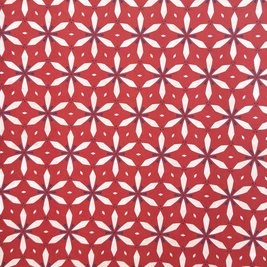 a sheet of wrapping paper with a floral geometric design in white and navy on red