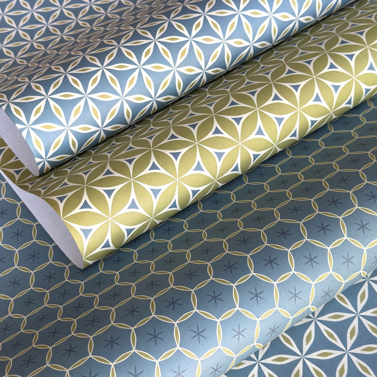 Three sheets of patterned paper with geometric designs on a blue background.