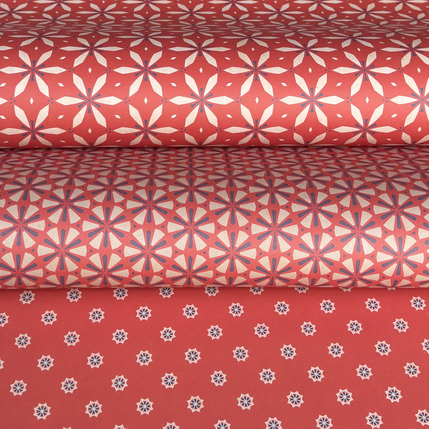 Three rolls of red wrapping paper with geometric patterns