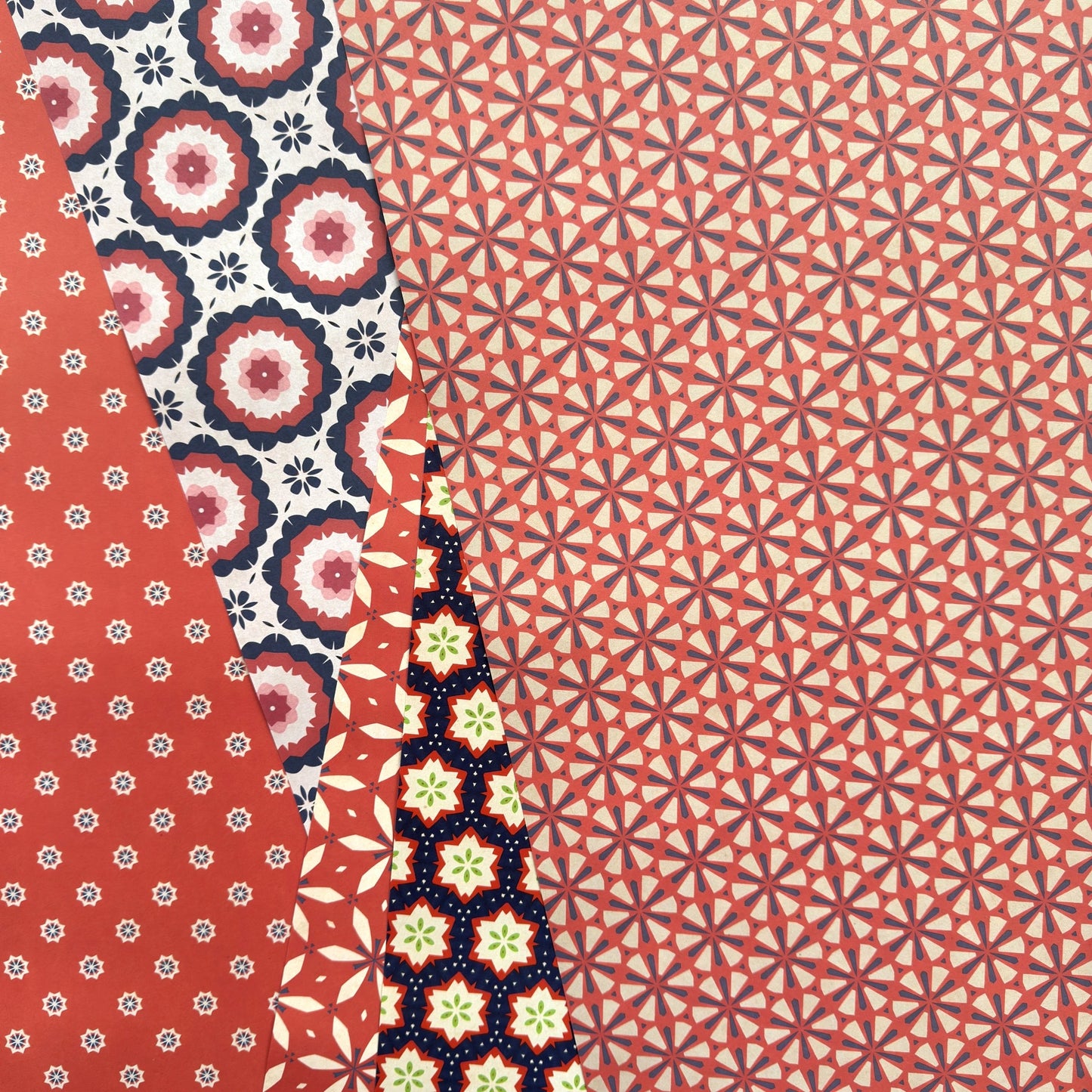 five sheets of different geometric wrapping papers in colours of red, purple and white