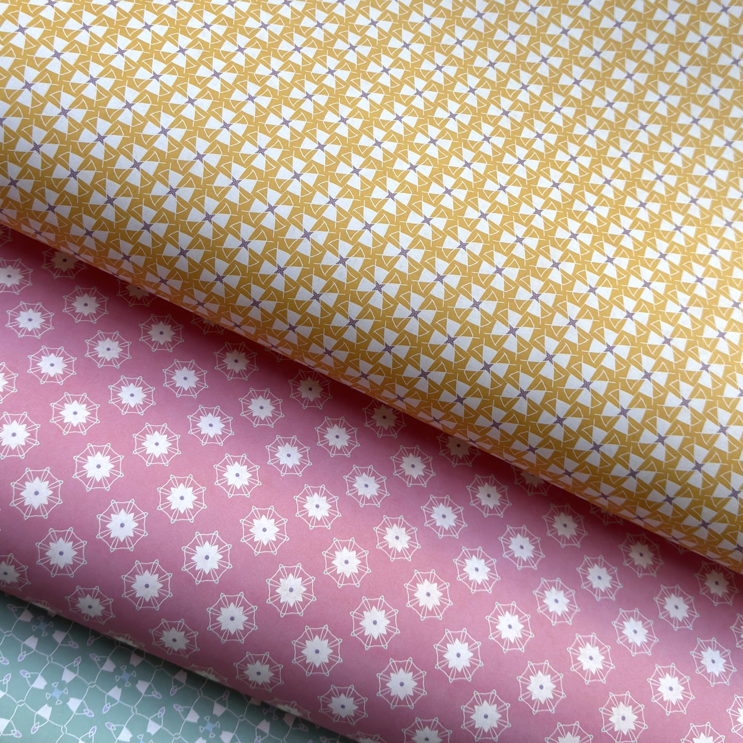 Three sheets of patterned paper in yellow, pink, and green.