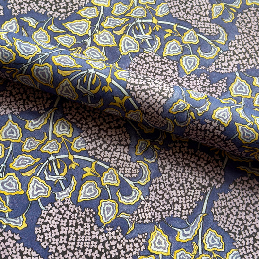 wrapping paper with a stylised lilac flower pattern in lilac , yellow and white, pictured rolled