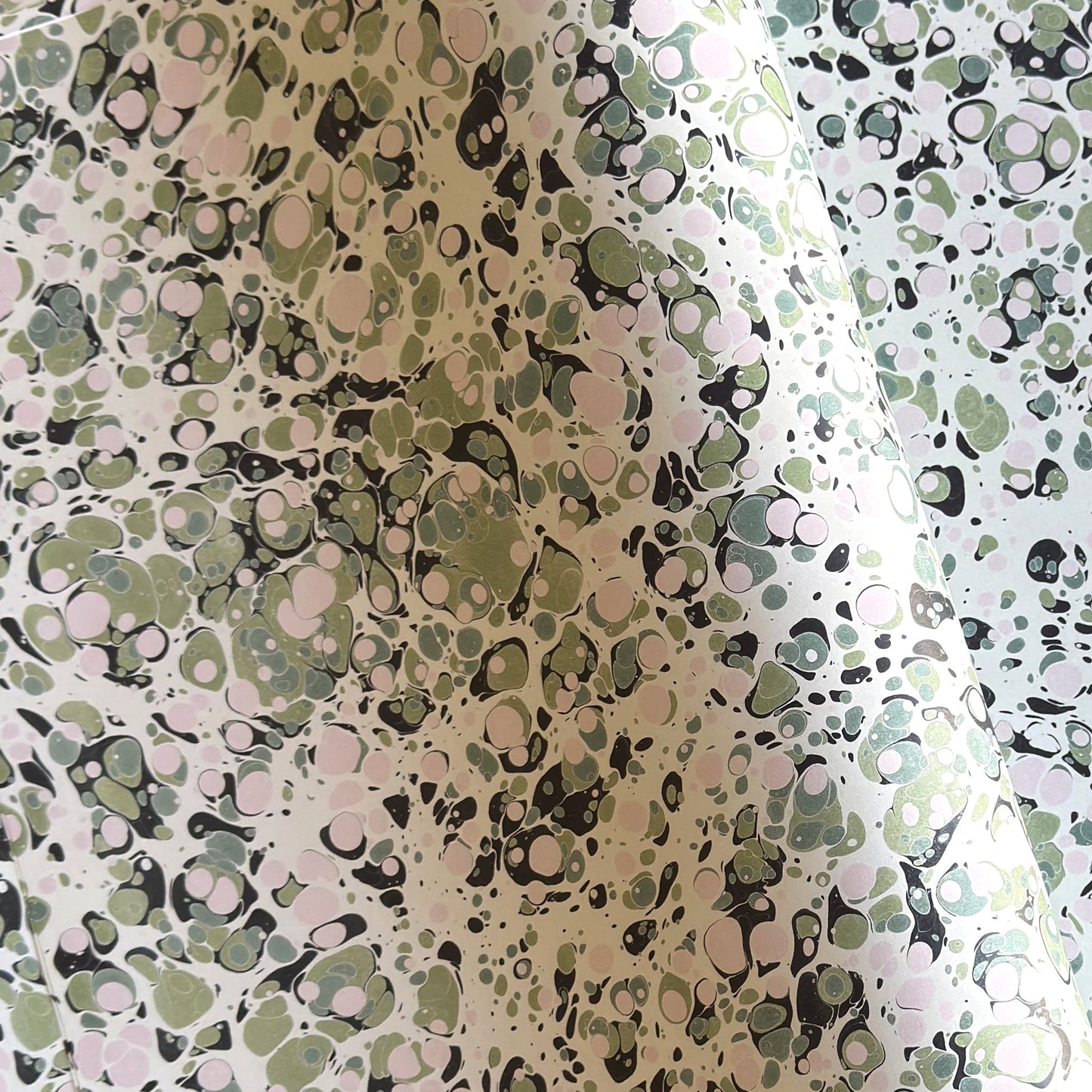 marbled printed wrapping paper with spot design in moss green, pale pink on a soft green.