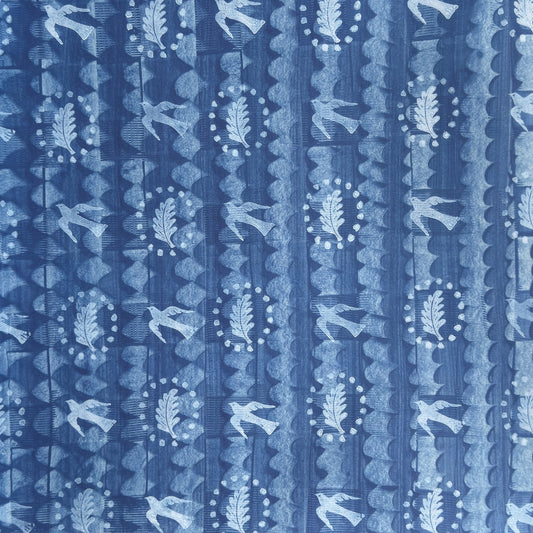 a sheet of wrapping paper with a relief printed oak leaf and bird in white on a blue paste paper backdrop