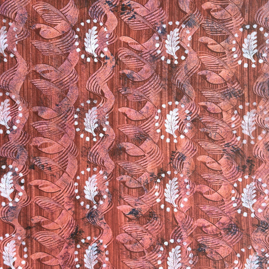 a sheet of wrapping paper with a relief printed oak leaf in white on a rust brown paste paper backdrop