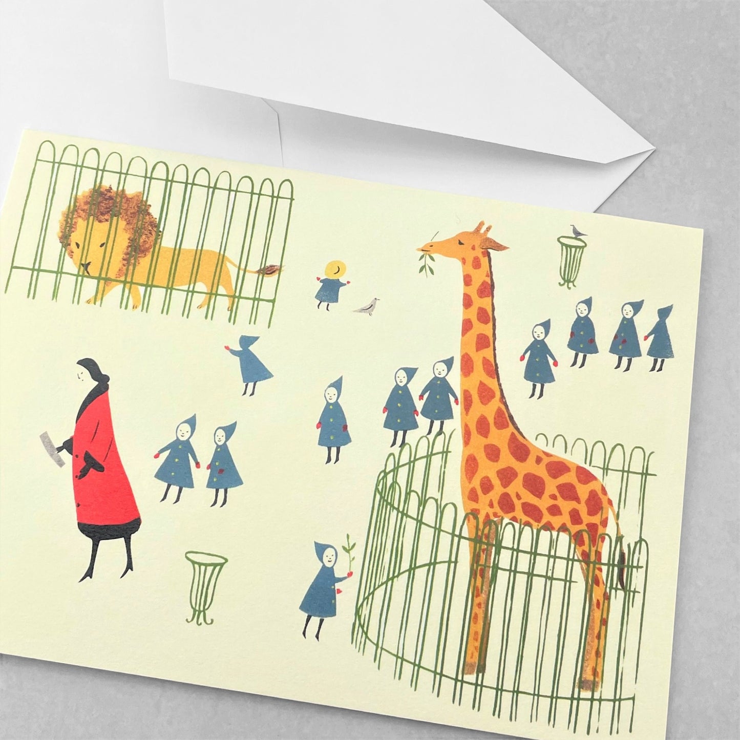 greetings card showing a drawing of a women in a red coat walking young children though a zoo with a lion and a giraffe by Elizabeth Harbour
