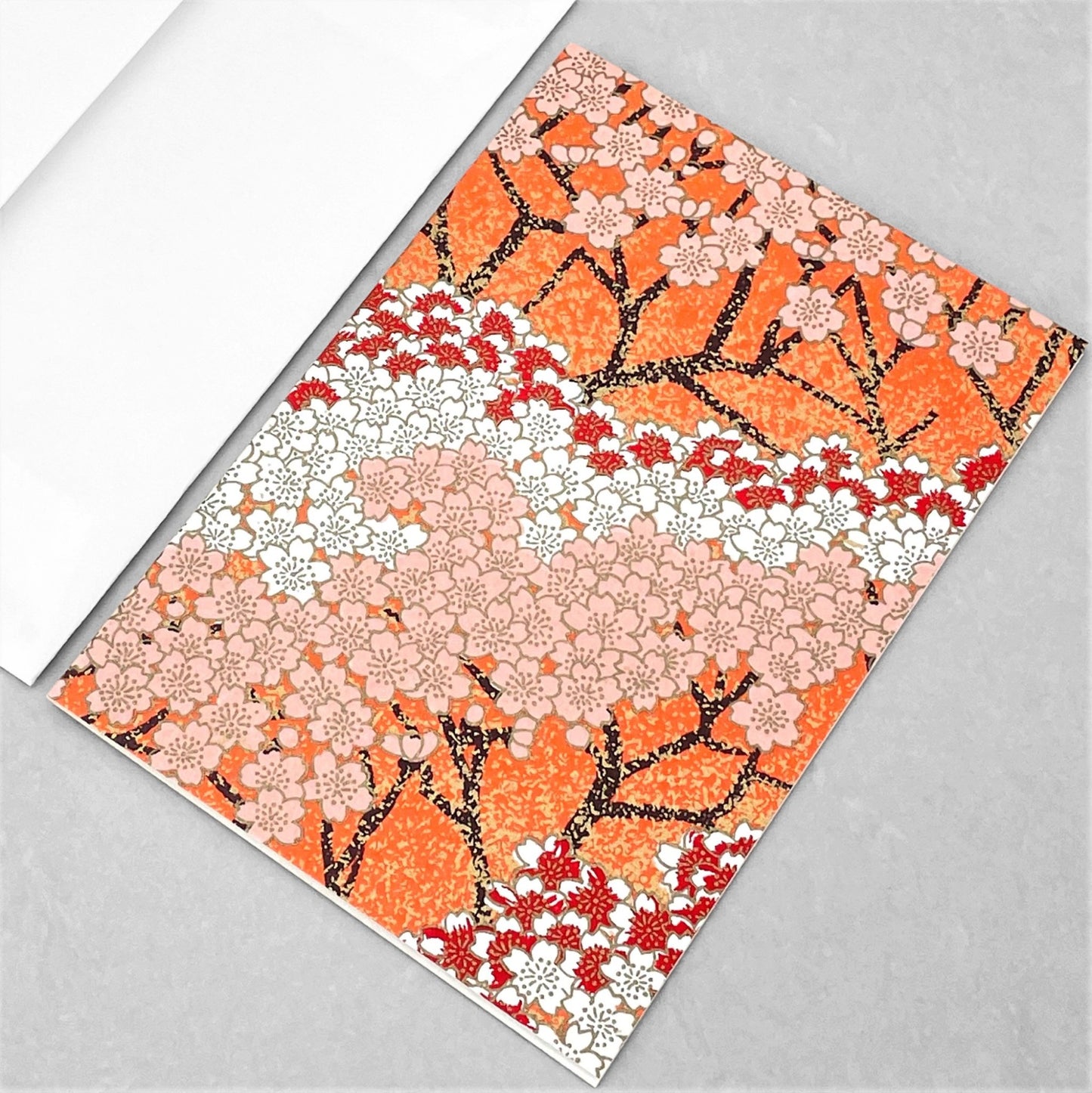 japanese silk-screen printed greetings card with a pattern of peach, white and red blossom branches on an orange backdrop by Esmie