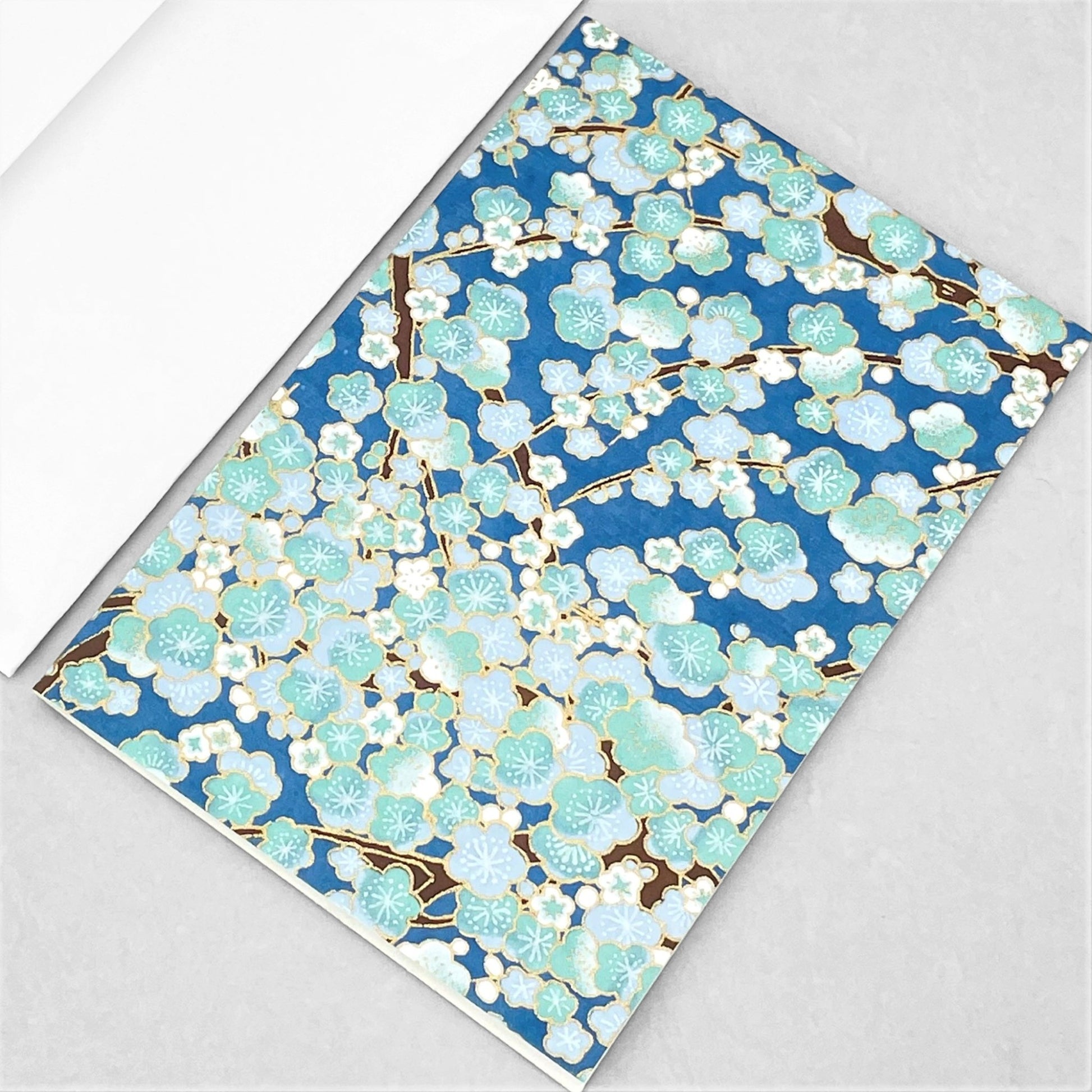 japanese silk-screen printed greetings card with a pattern of pale blue and white blossom on a blue backdrop by Esmie