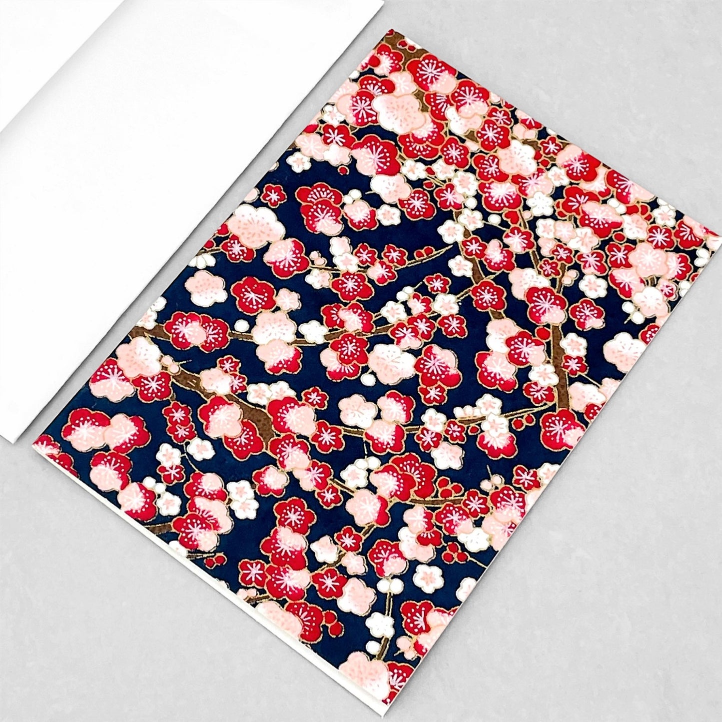 japanese silk-screen printed greetings card with a repeat pattern of pink and red blossom branches on a dark blue backdrop by Esmie