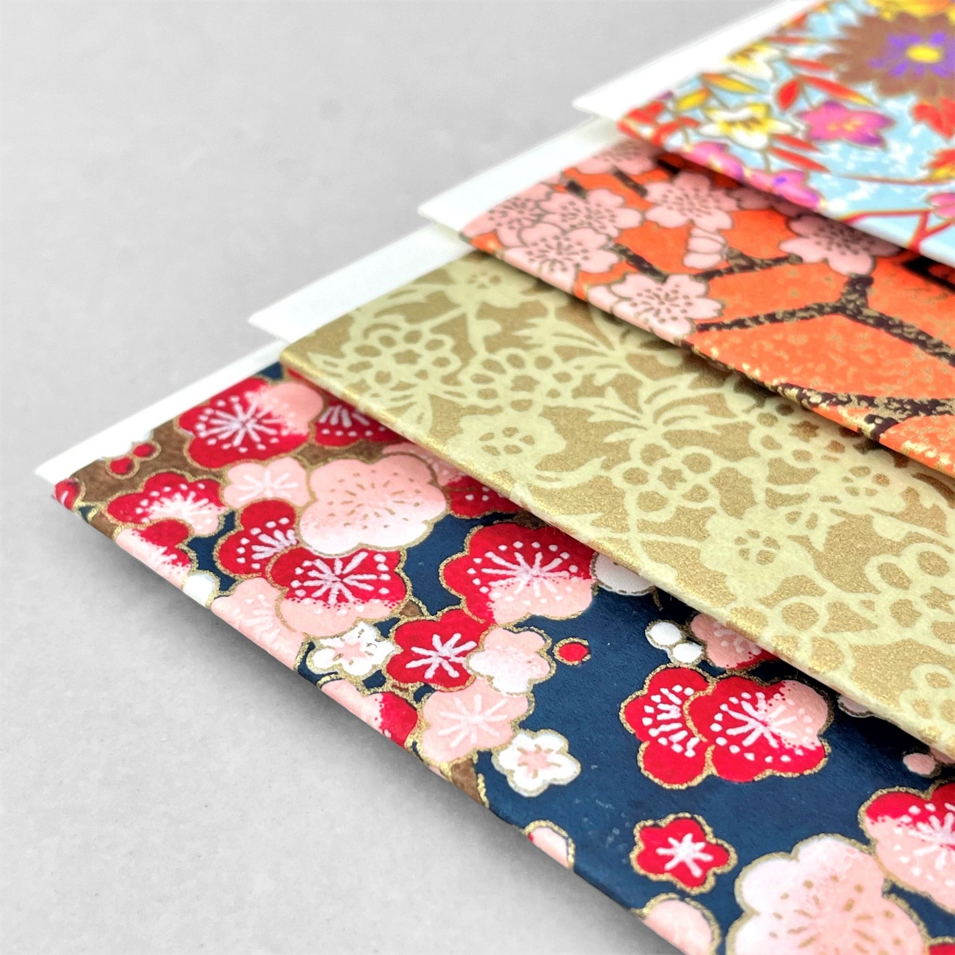 japanese silk-screen printed greetings card with a repeat pattern of pink and red blossom branches on a dark blue backdrop by Esmie