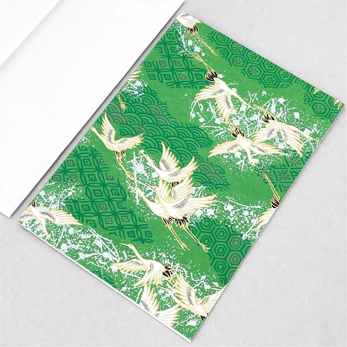 japanese silk-screen printed greetings card with a pattern of white cranes in flight on a green backdrop of japanese motifs by Esmie