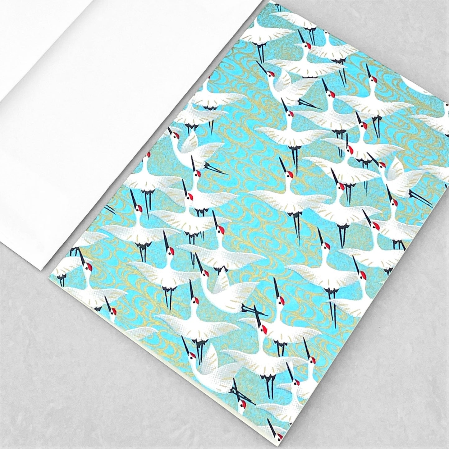 japanese silk-screen printed greetings card with a repeat diagonal pattern of white cranes on an aqua backdrop by Esmie