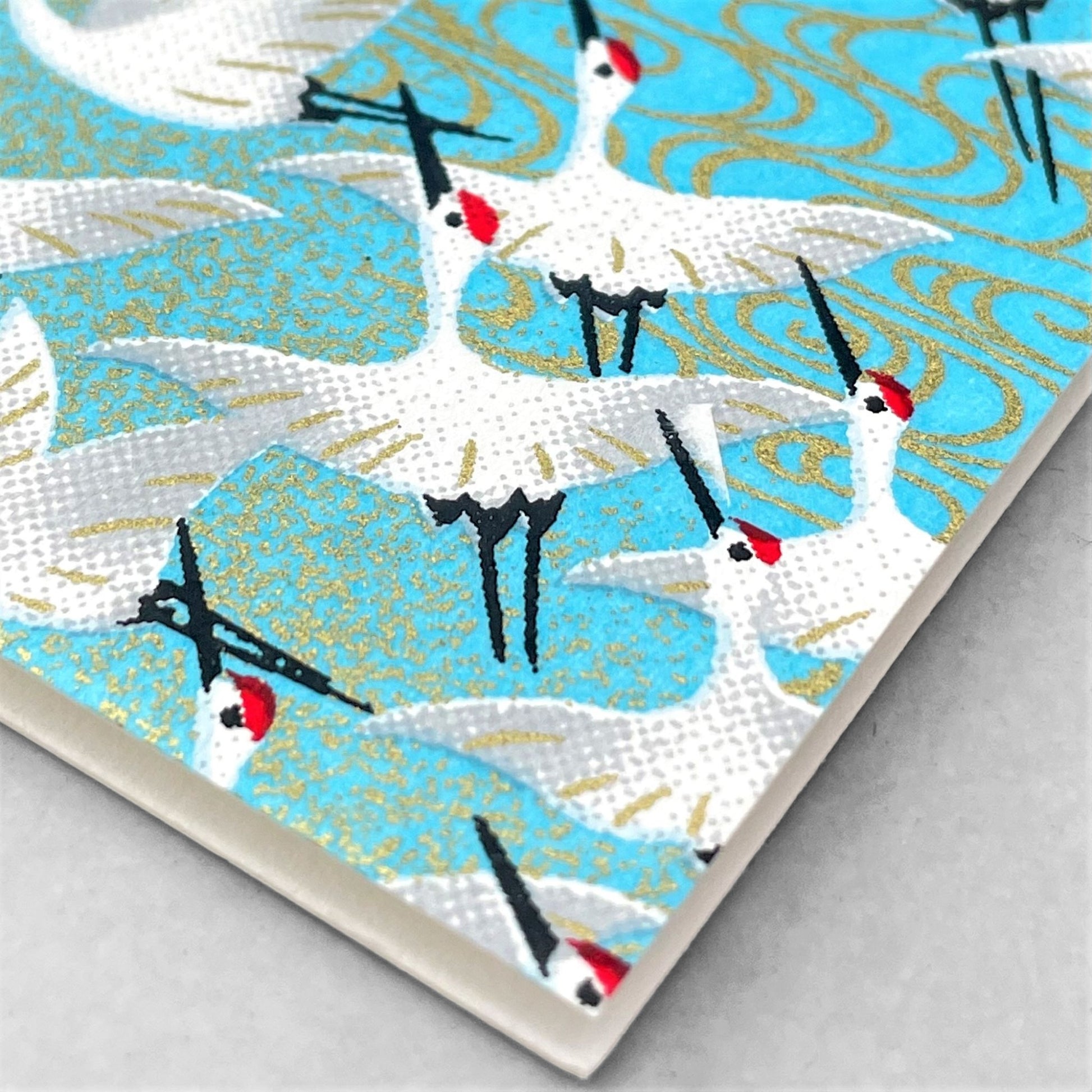 japanese silk-screen printed greetings card with a repeat diagonal pattern of white cranes on an aqua backdrop by Esmie