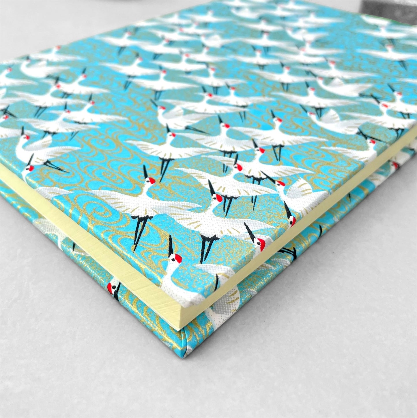 hardback A5 plain notebook with cover made of japanese silkscreen chiyogami paper. White cranes in flight on a pale blue background by Esmie