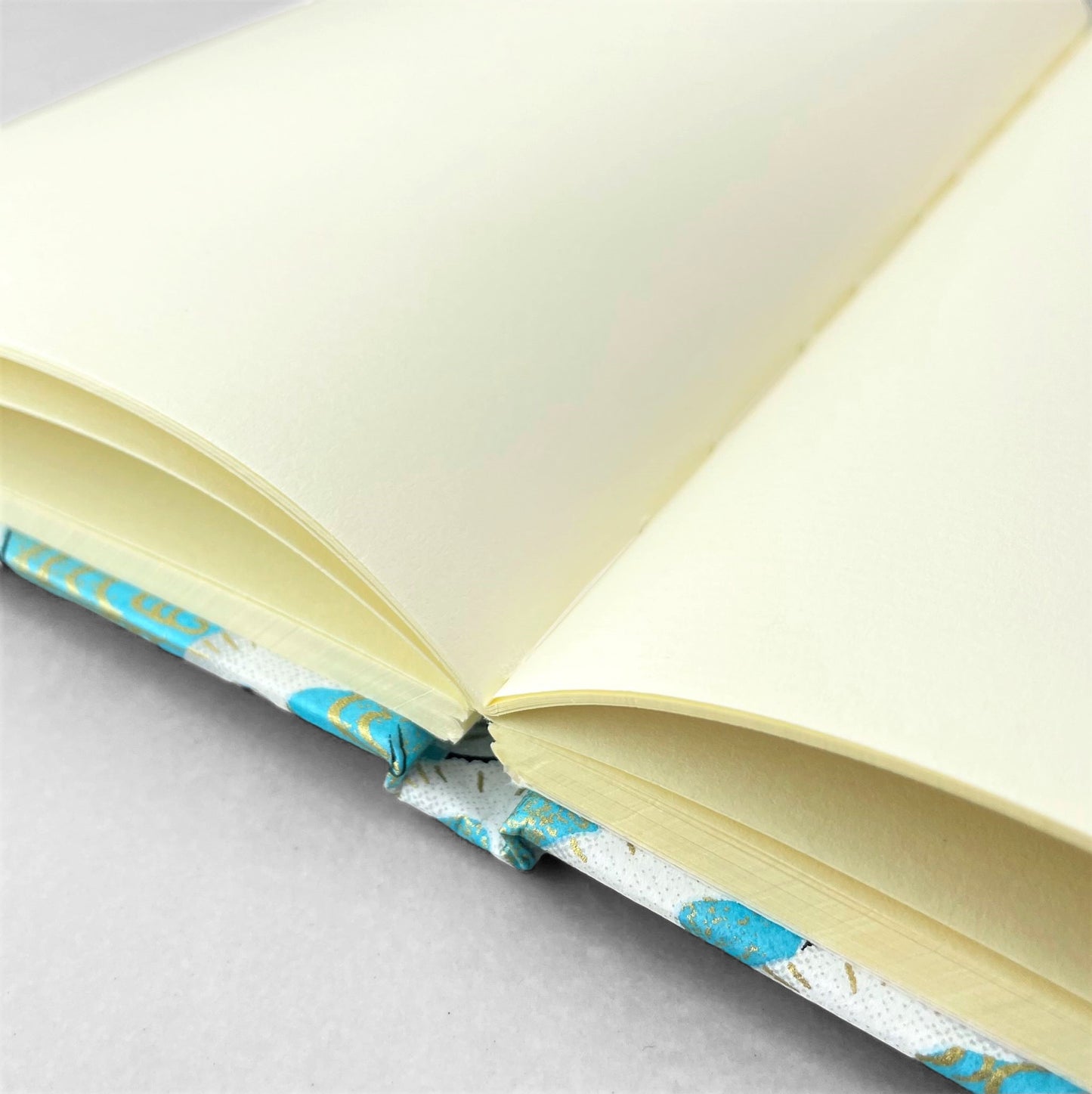 hardback A5 plain notebook with cover made of japanese silkscreen chiyogami paper. White cranes in flight on a pale blue background by Esmie