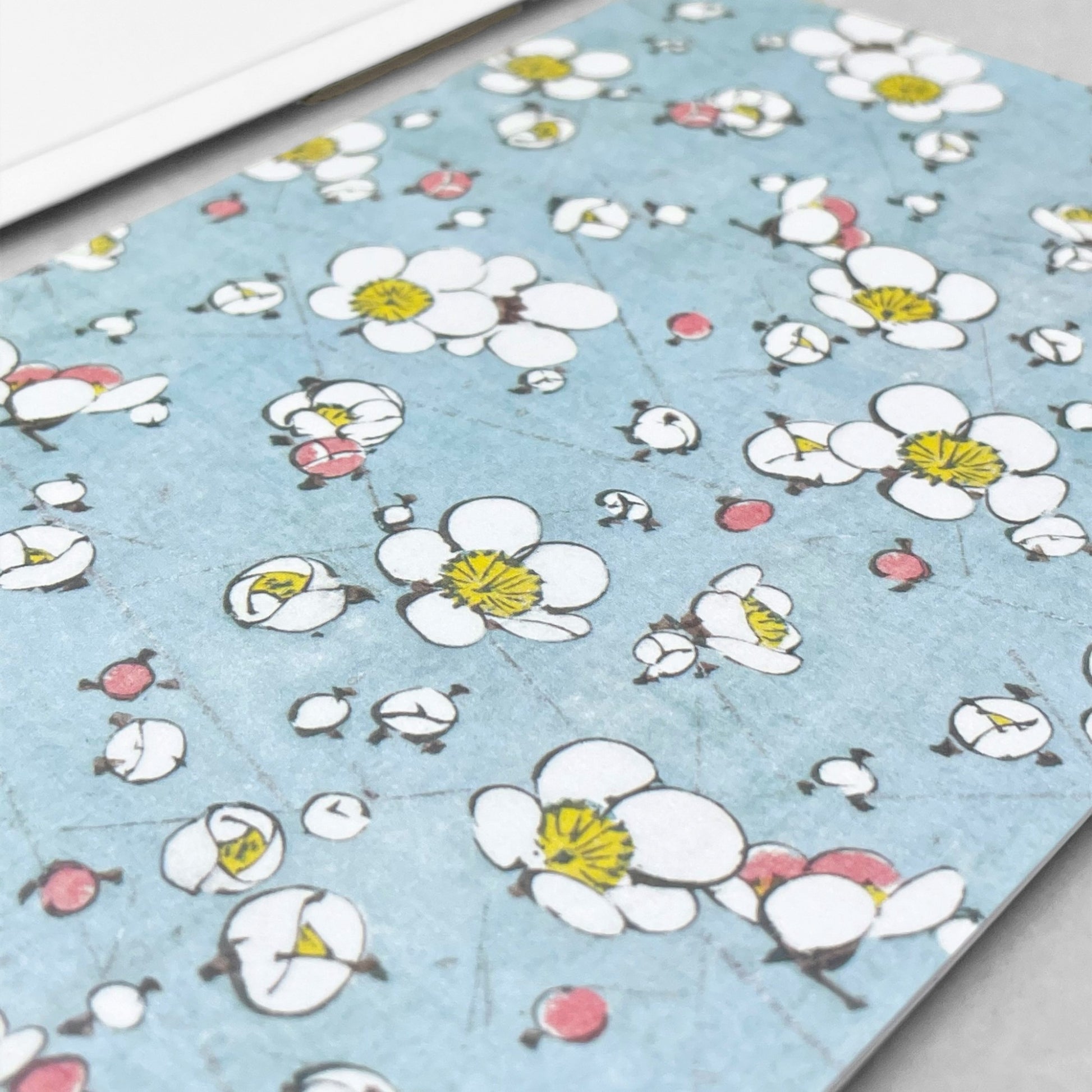 greetings card with a repeat pattern of plum blossom on pale blue backdrop by Ezen Design