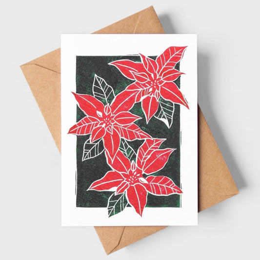 Greeting card with a linocut print of a poinsetta in red and green with a craft envelope