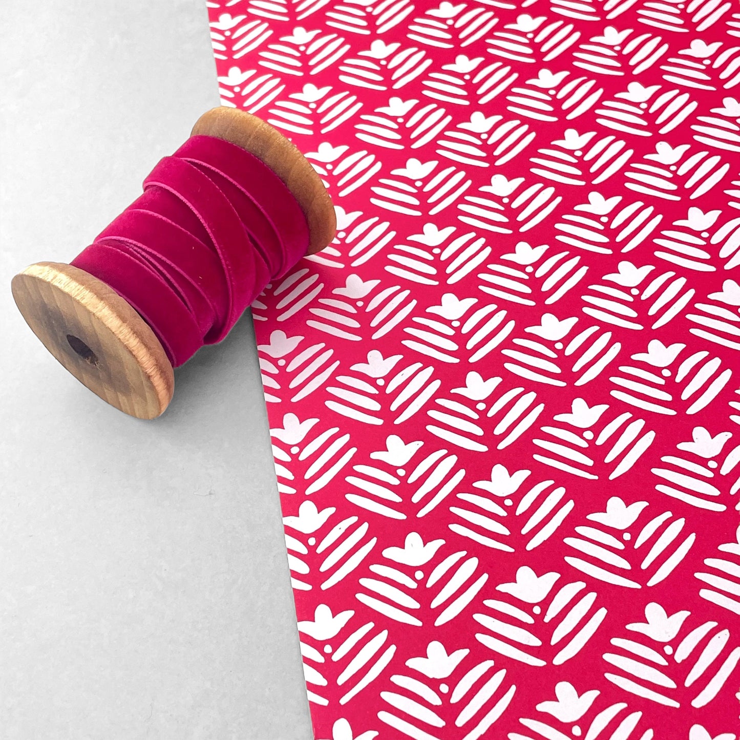 wrapping paper with magenta backdrop and a white flower repeat pattern by Heather Evelyn