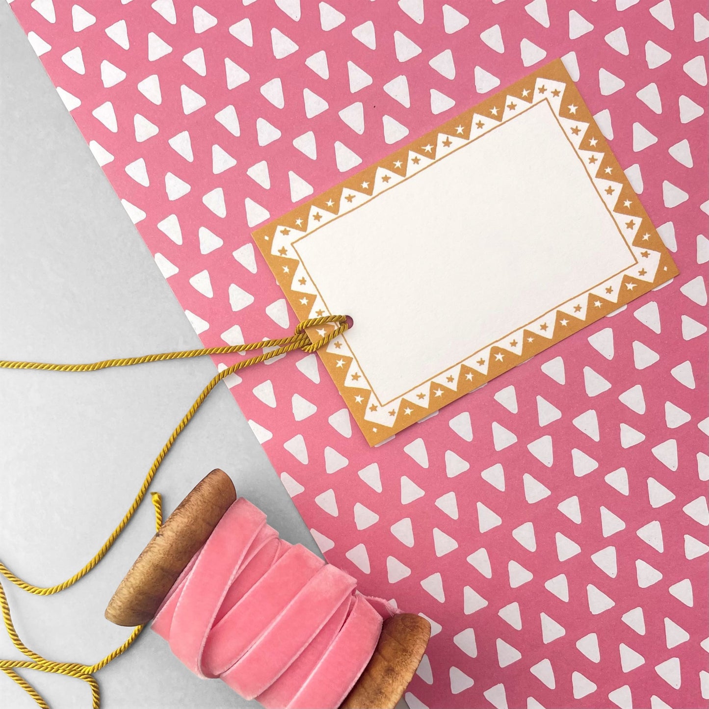 wrapping paper with pink background and repeat pattern of little white triangles by Heather Evelyn