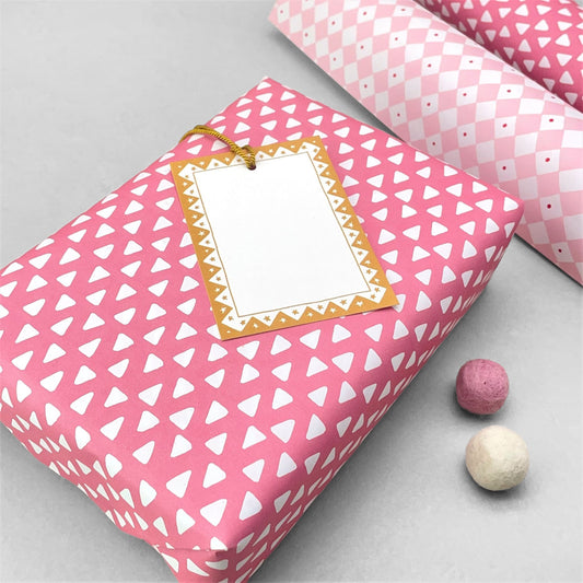 wrapping paper with pink background and repeat pattern of little white triangles by Heather Evelyn