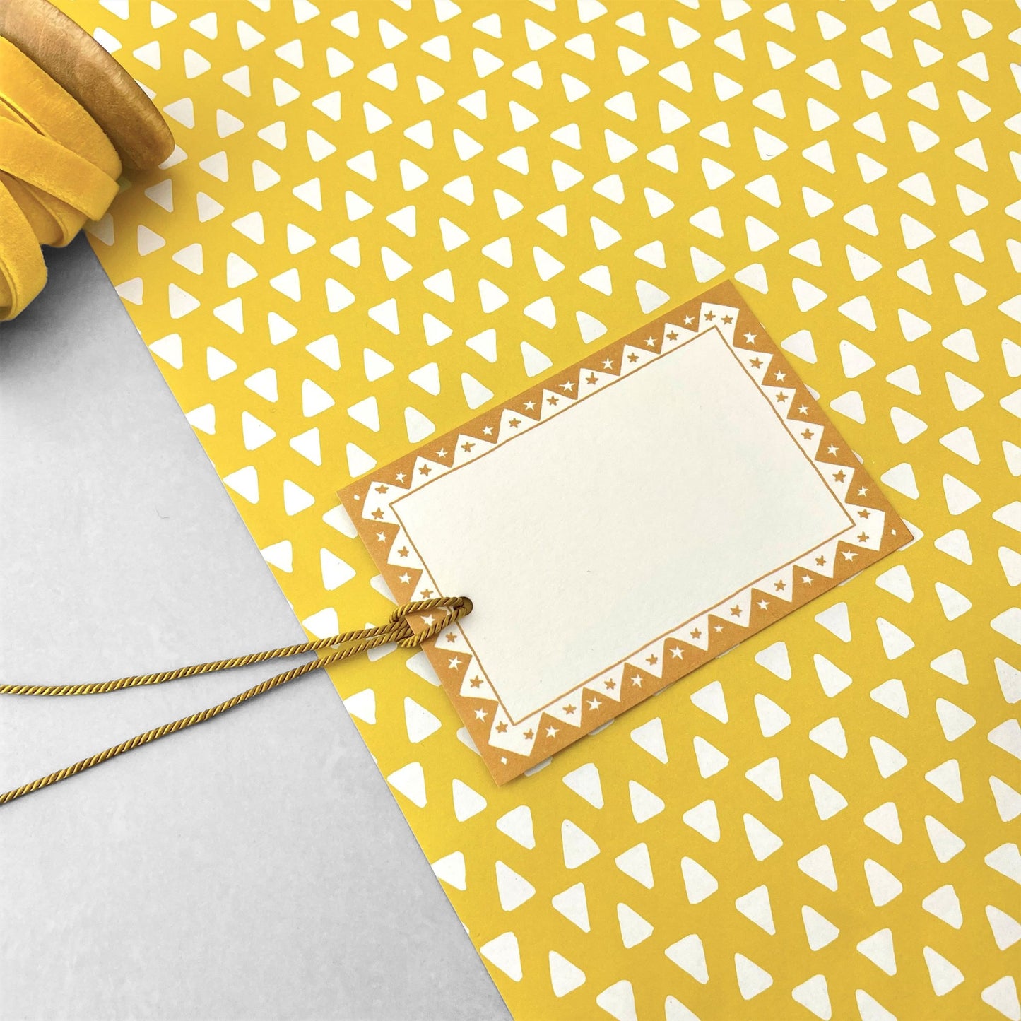 wrapping paper with yellow background and repeat pattern of little white triangles by Heather Evelyn