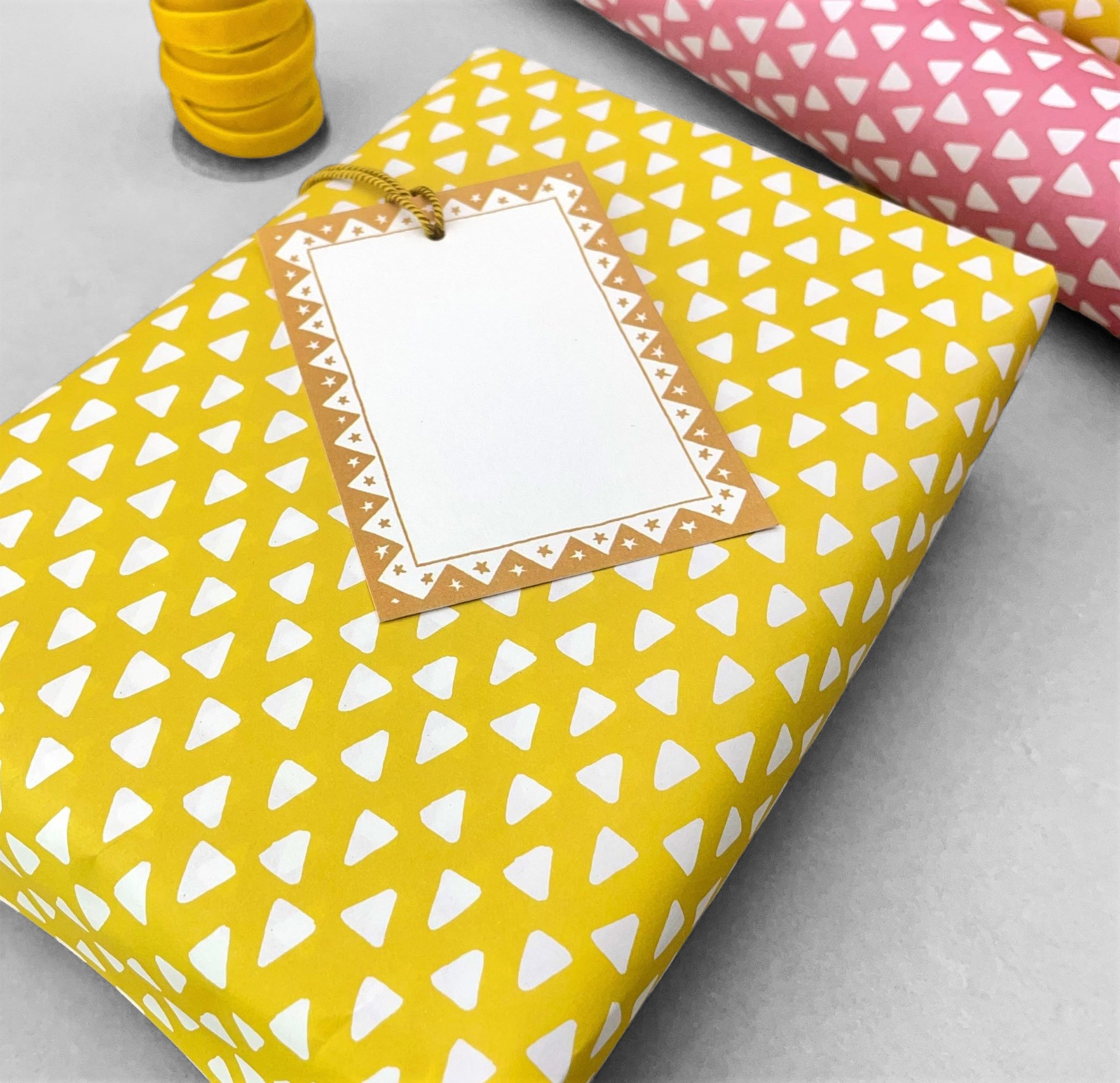 wrapping paper with yellow background and repeat pattern of little white triangles by Heather Evelyn