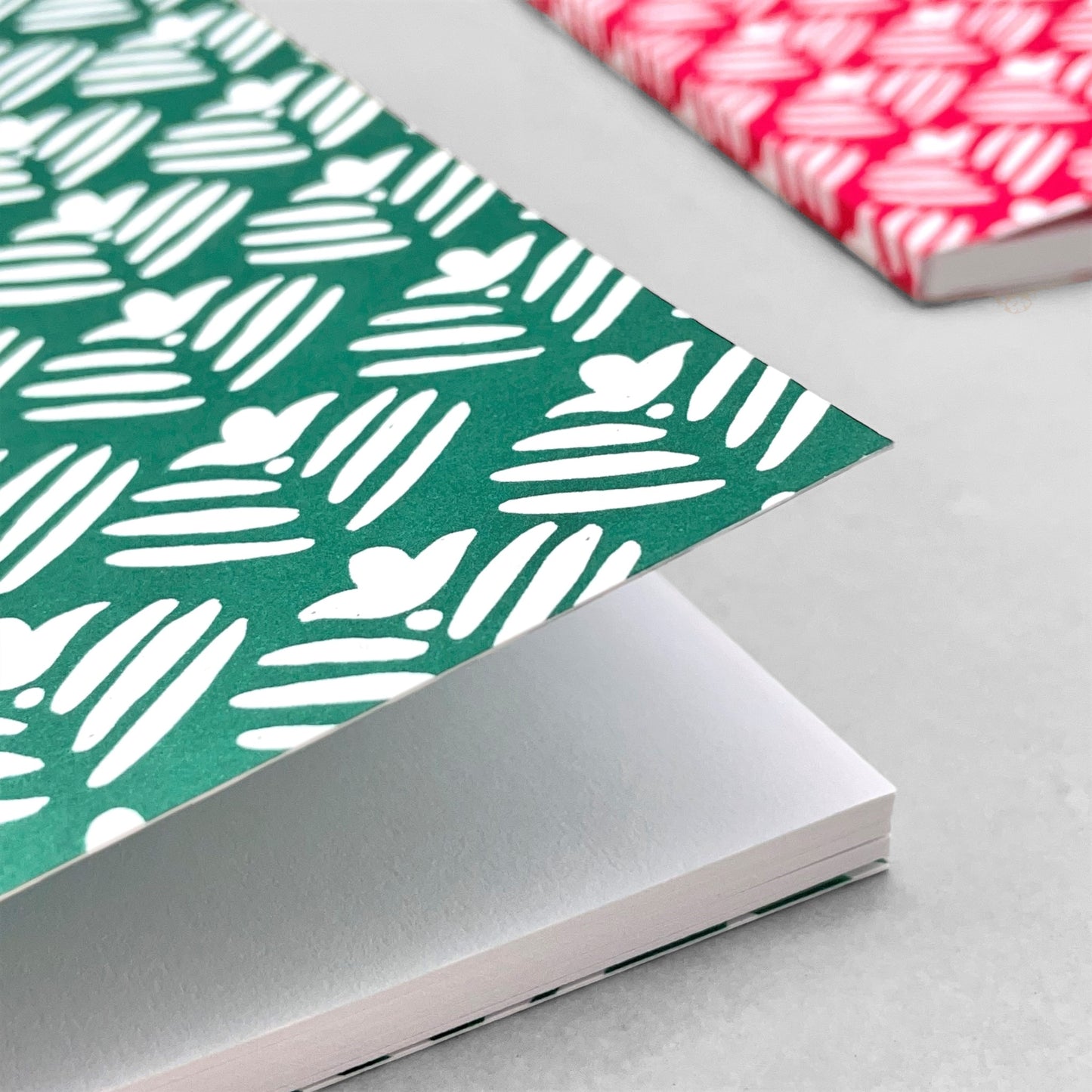 A5 notebook with dark green cover and a repeat pattern of white flowers by Heather Evelyn
