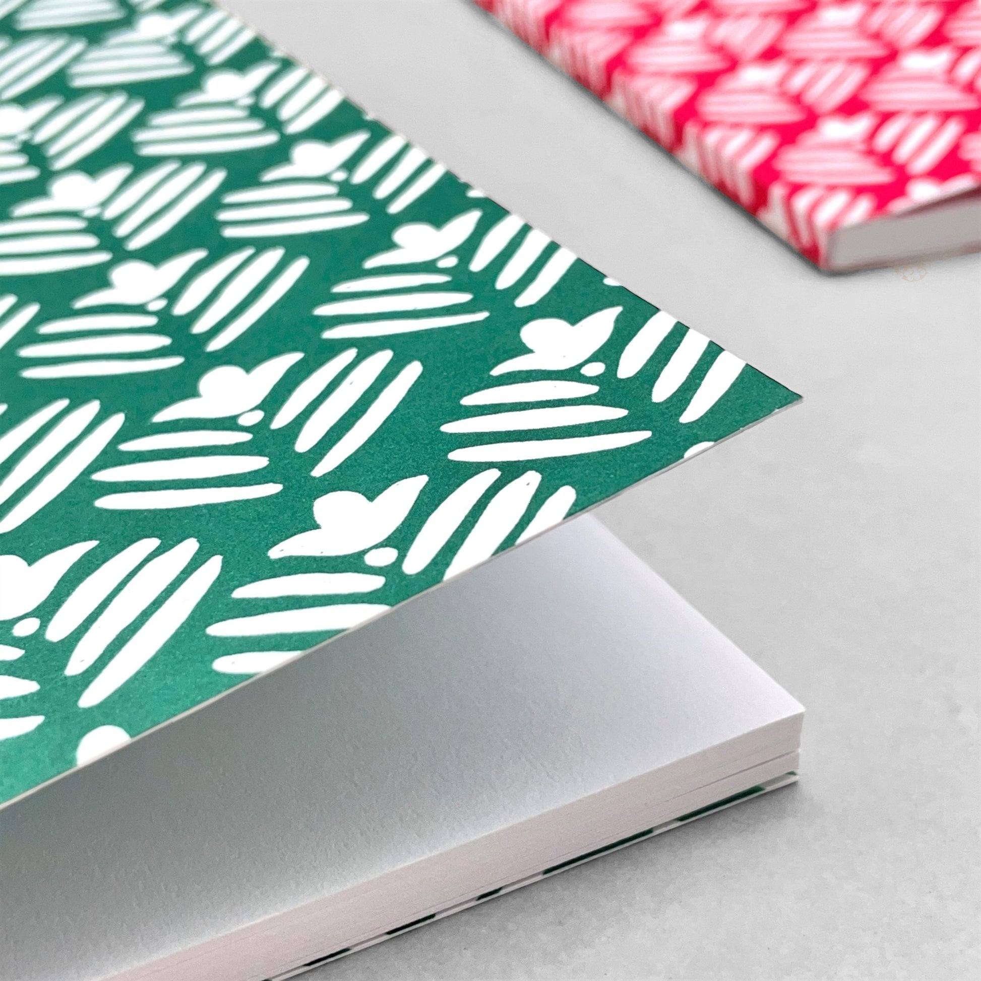 A5 notebook with dark green cover and a repeat pattern of white flowers by Heather Evelyn