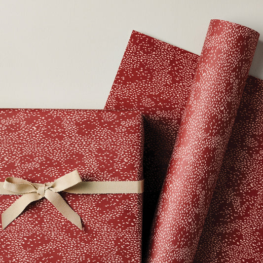 a sheet of wrapping paper in rust with an abstract pink speckled design