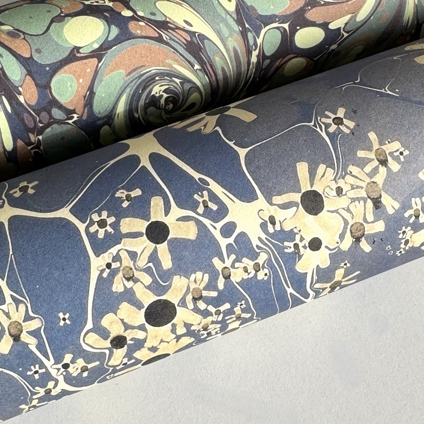 printed marble design wrapping paper by Jemma Lewis.  Daisy flower design in white and black on blue backdrop. Close up
