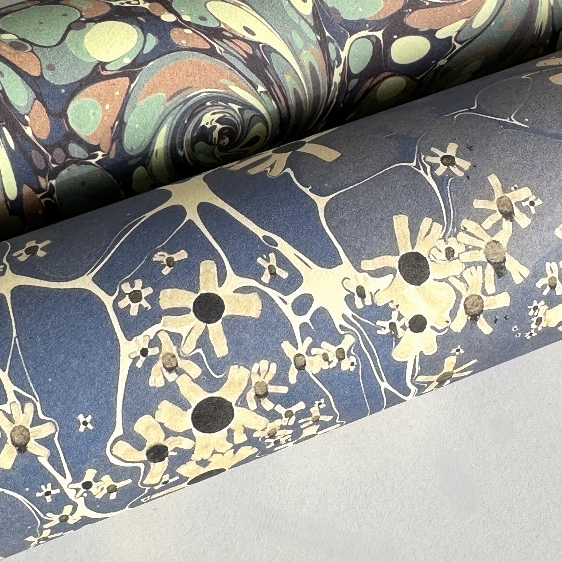 printed marble design wrapping paper by Jemma Lewis.  Daisy flower design in white and black on blue backdrop. Close up