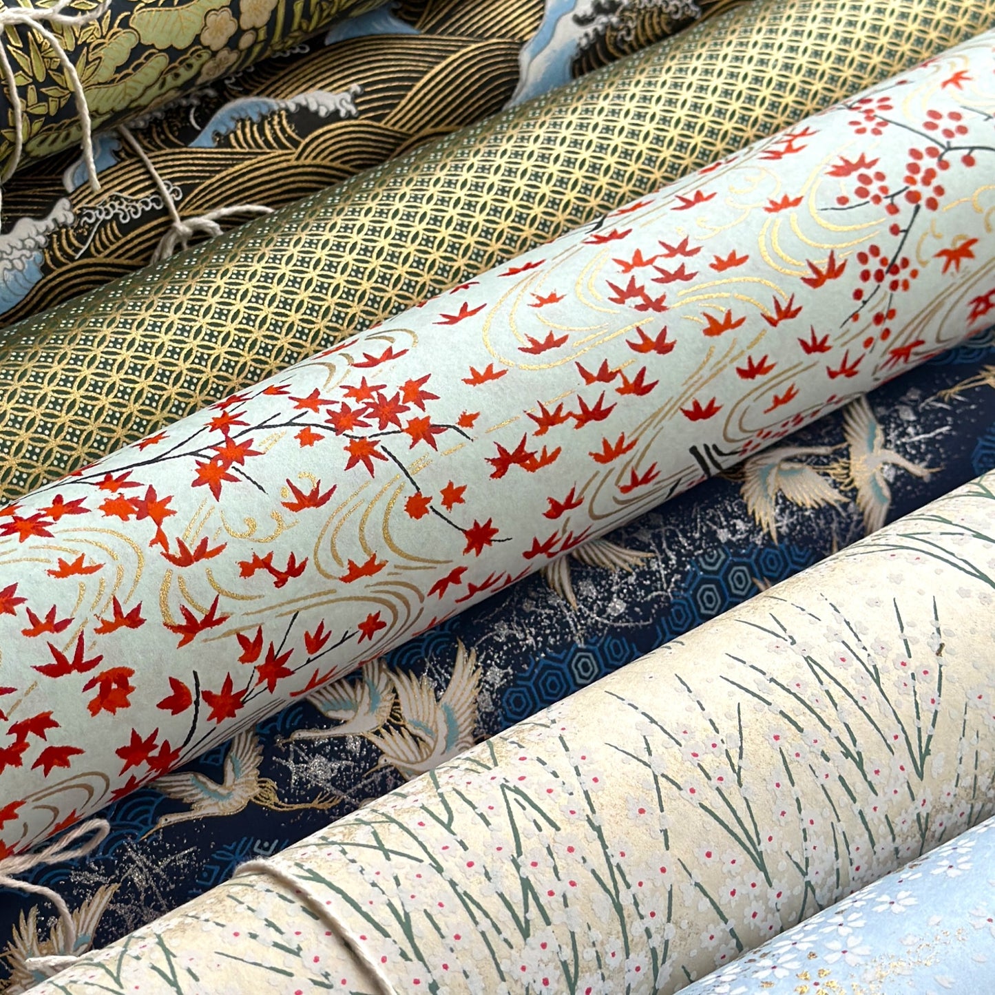 a sheet of japanese silkscreen printed chiyogami paper with a pattern of gold rivers, red falling leaves on a soft aqua background