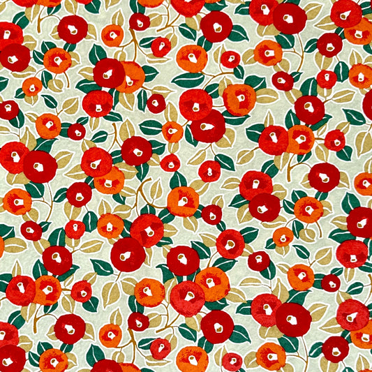 Japanese silkscreen chiyogami paper with a repeat pattern of camellia flowers in red and orange on a soft green ground