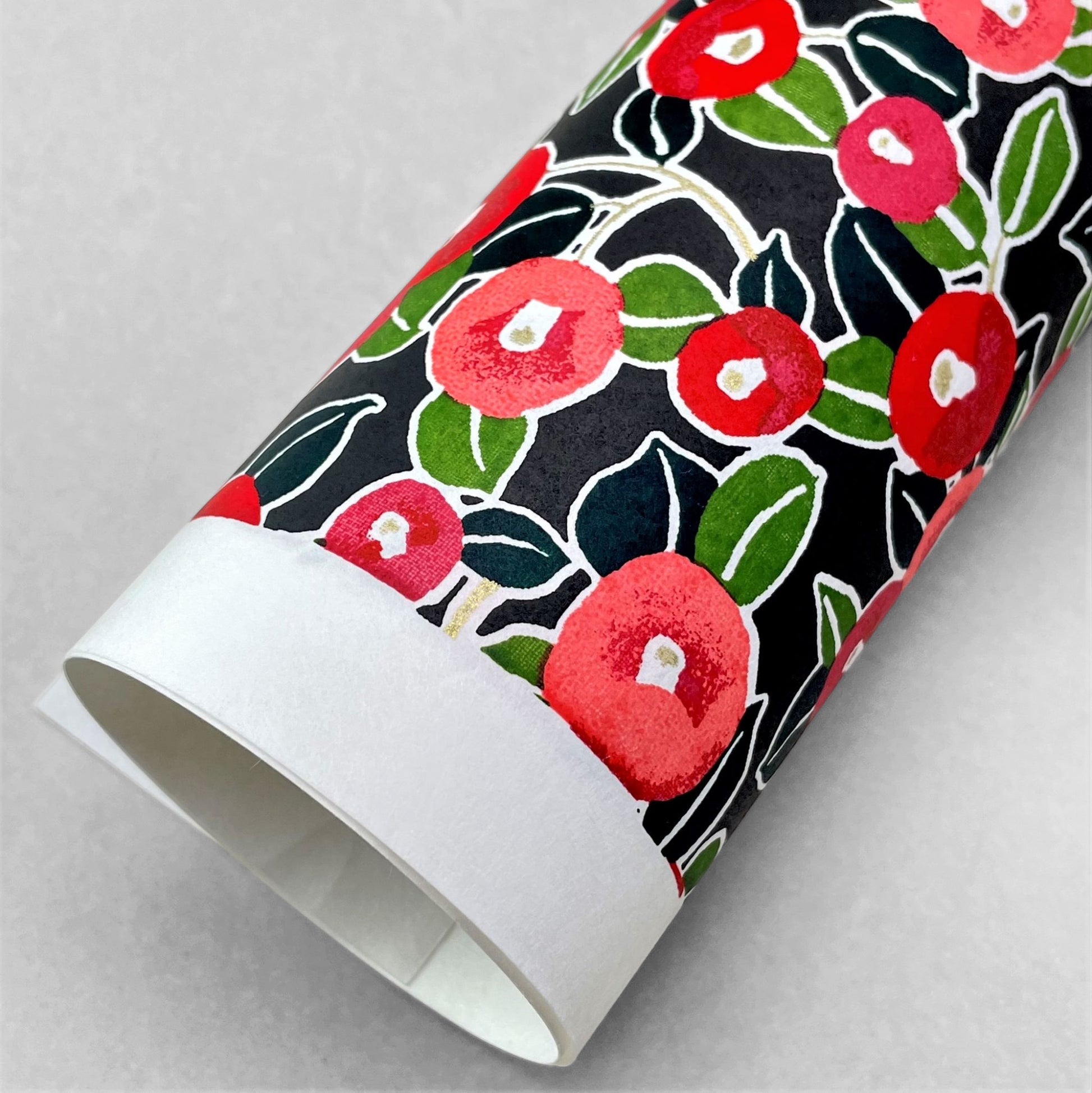 japanese silk-screen handmade paper, chiyogami, with a design showing red and pink morning glory flowers and green leaves on black background