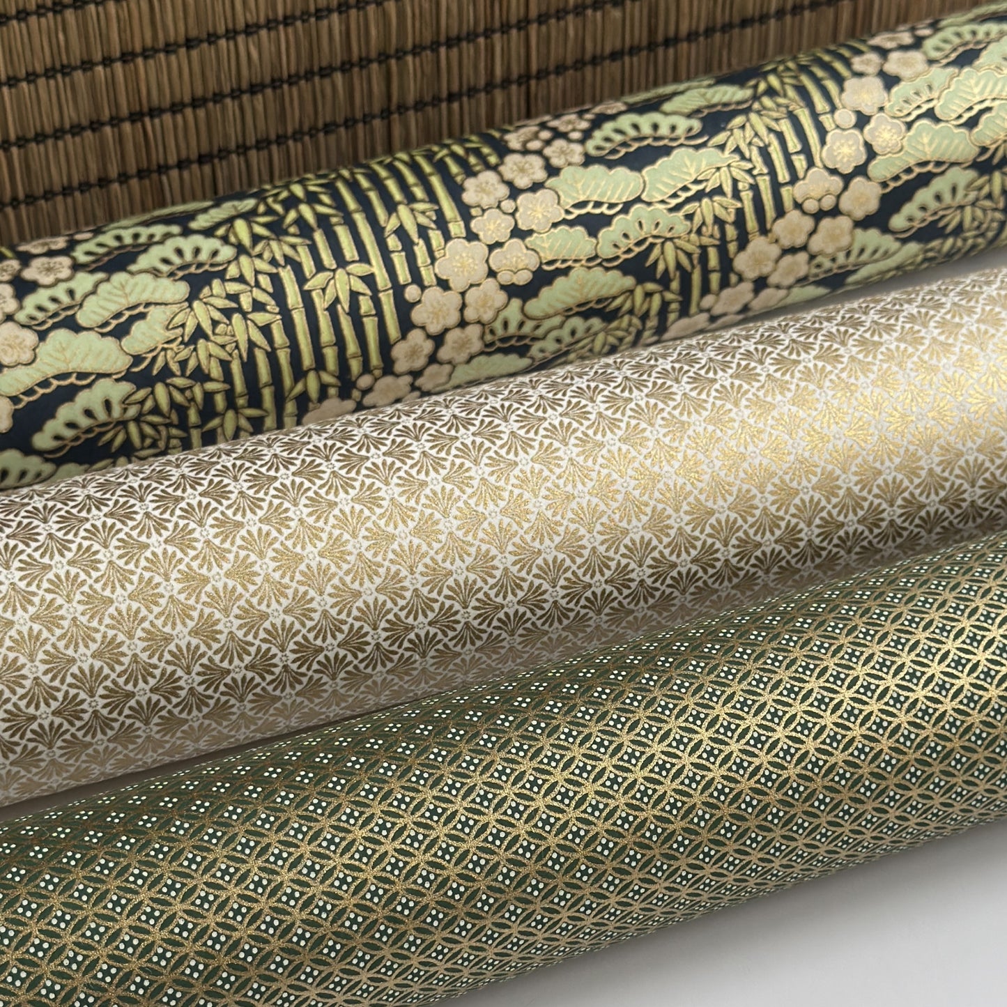 a sheet of Japanese silkscreen printed chiyogami paper with a design of trees, bamboo and plum blossom in a palette of mint green, white and dark indigo