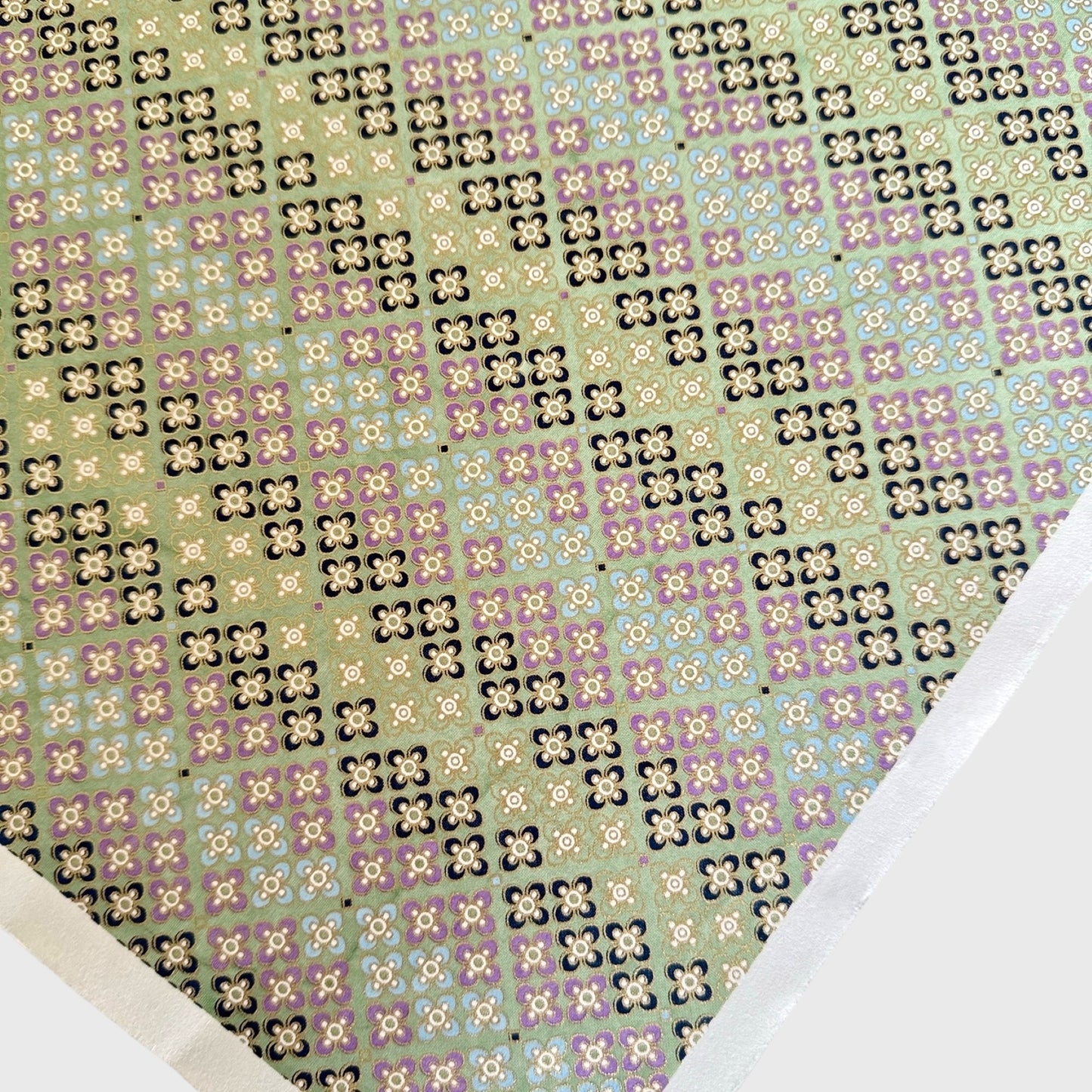 Japanese silkscreen chiyogami paper with a repeat pattern of stripes of a small floral motif in black, lilac and blue on a moss green backdrop