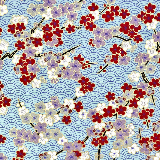Japanese silkscreen chiyogami paper with a pattern of deep red, lilac and white plum blossom on a blue backdrop