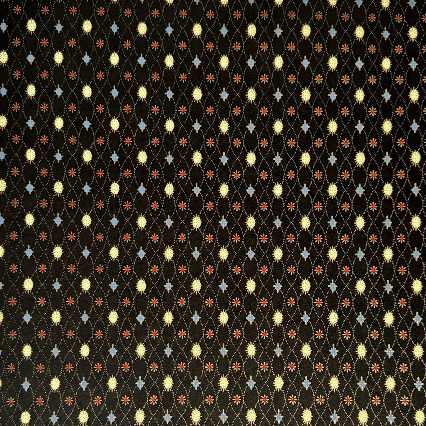 Japanese silkscreen chiyogami paper with a pattern of small repeat motifs in red, blue, lemon and gold on a black background