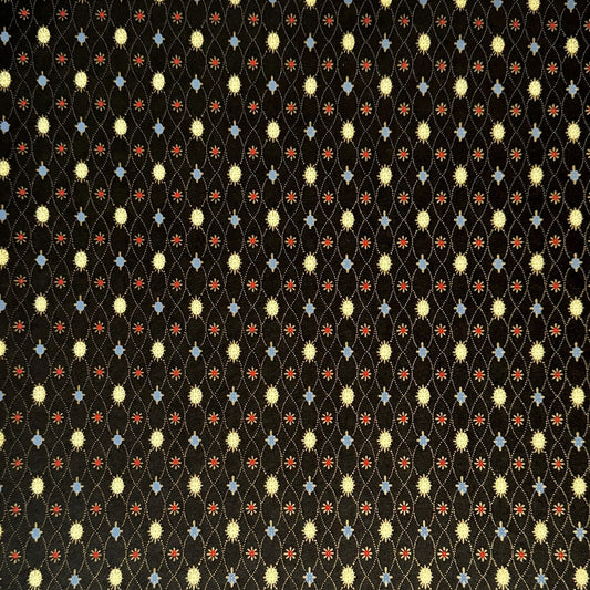 Japanese silkscreen chiyogami paper with a pattern of small repeat motifs in red, blue, lemon and gold on a black background