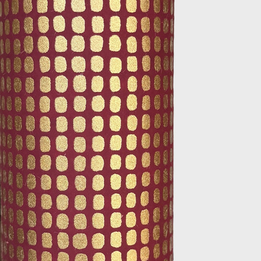 a sheet of Japanese chiyogami paper in rich claret red with a repeat pattern of gold rounded rectangles