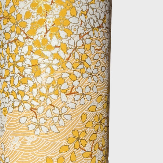 a sheet of Japanese chiyogami yuzen paper with a delicate pattern of little sakura cherry blossom in amber yellow and white