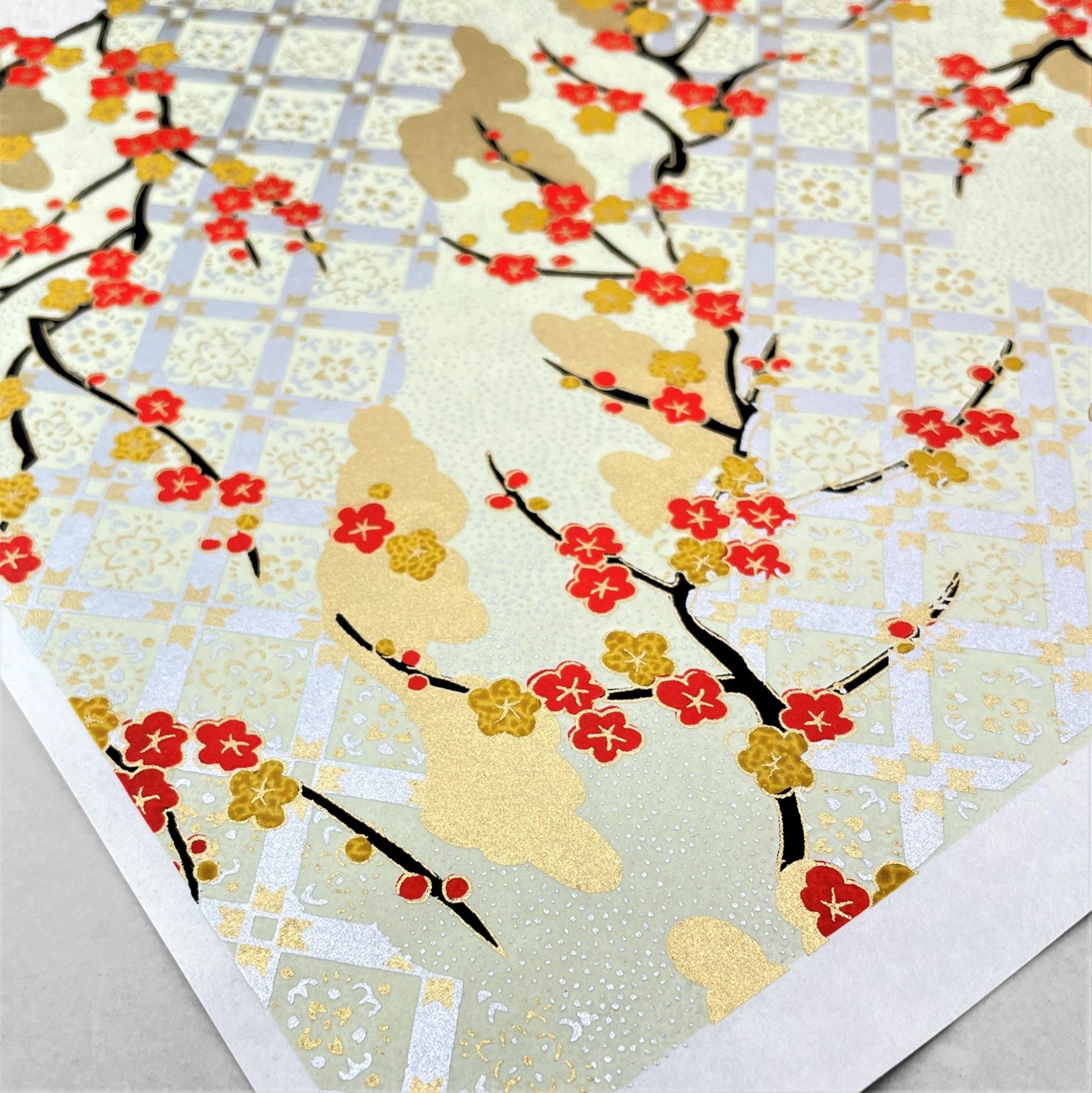 japanese silk-screen handmade paper, chiyogami, showing branches of red cherry blossom and gold clouds on a backdrop of silver, cream and gold